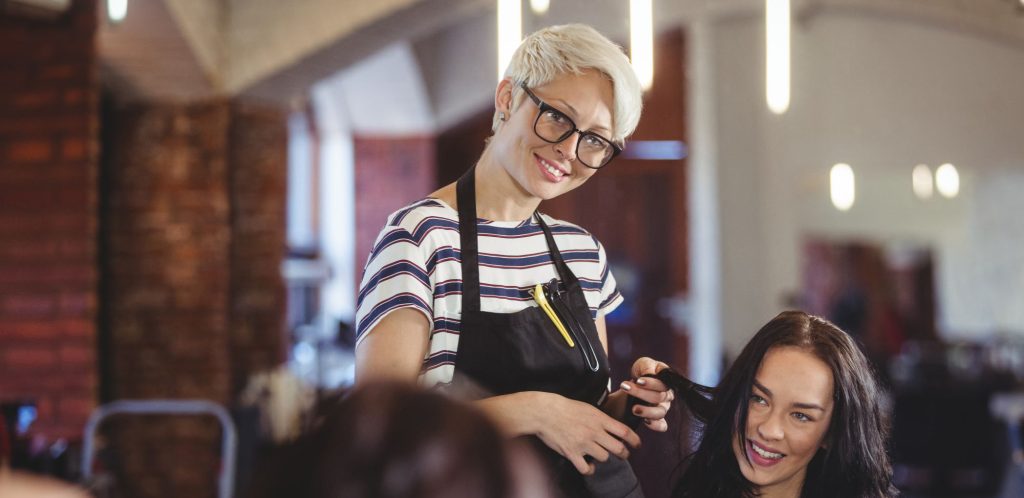 Woman styling another woman's hair in a salon